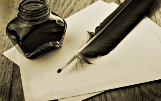 Plume et pot d'encre posés sur une feuille