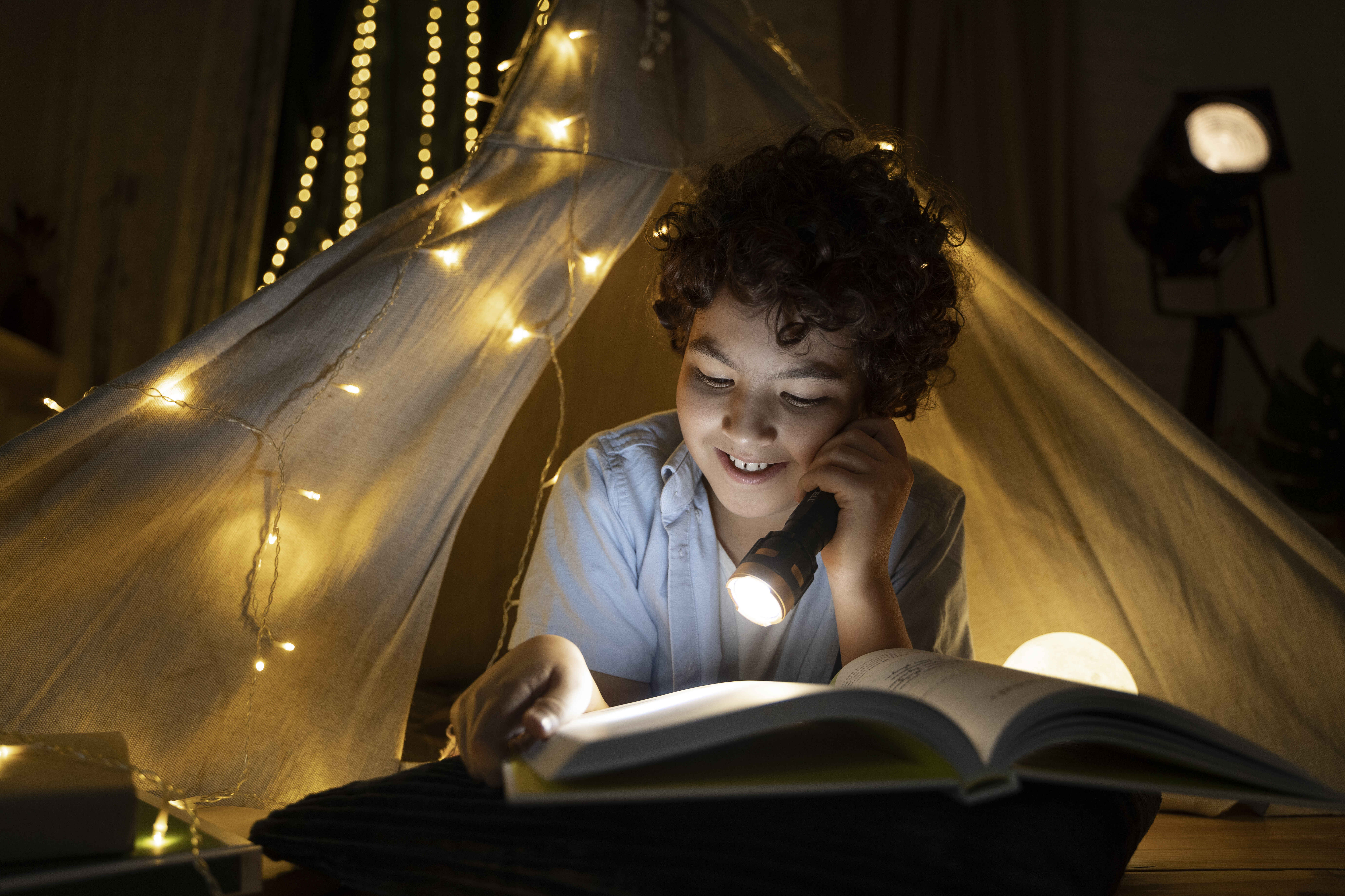 un enfant qui lit sous une tente