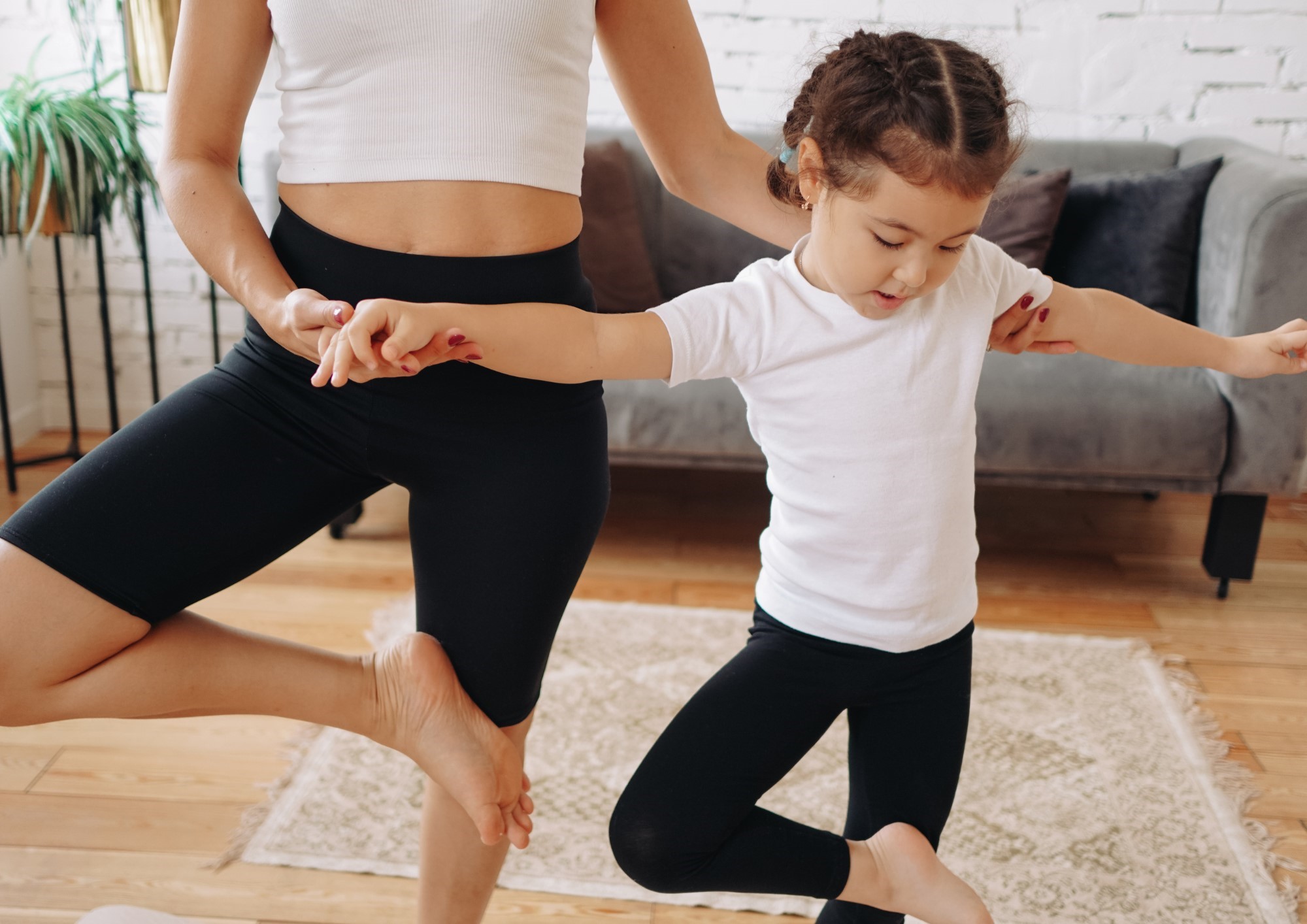 une enfant avec une adulte en posture de yoga