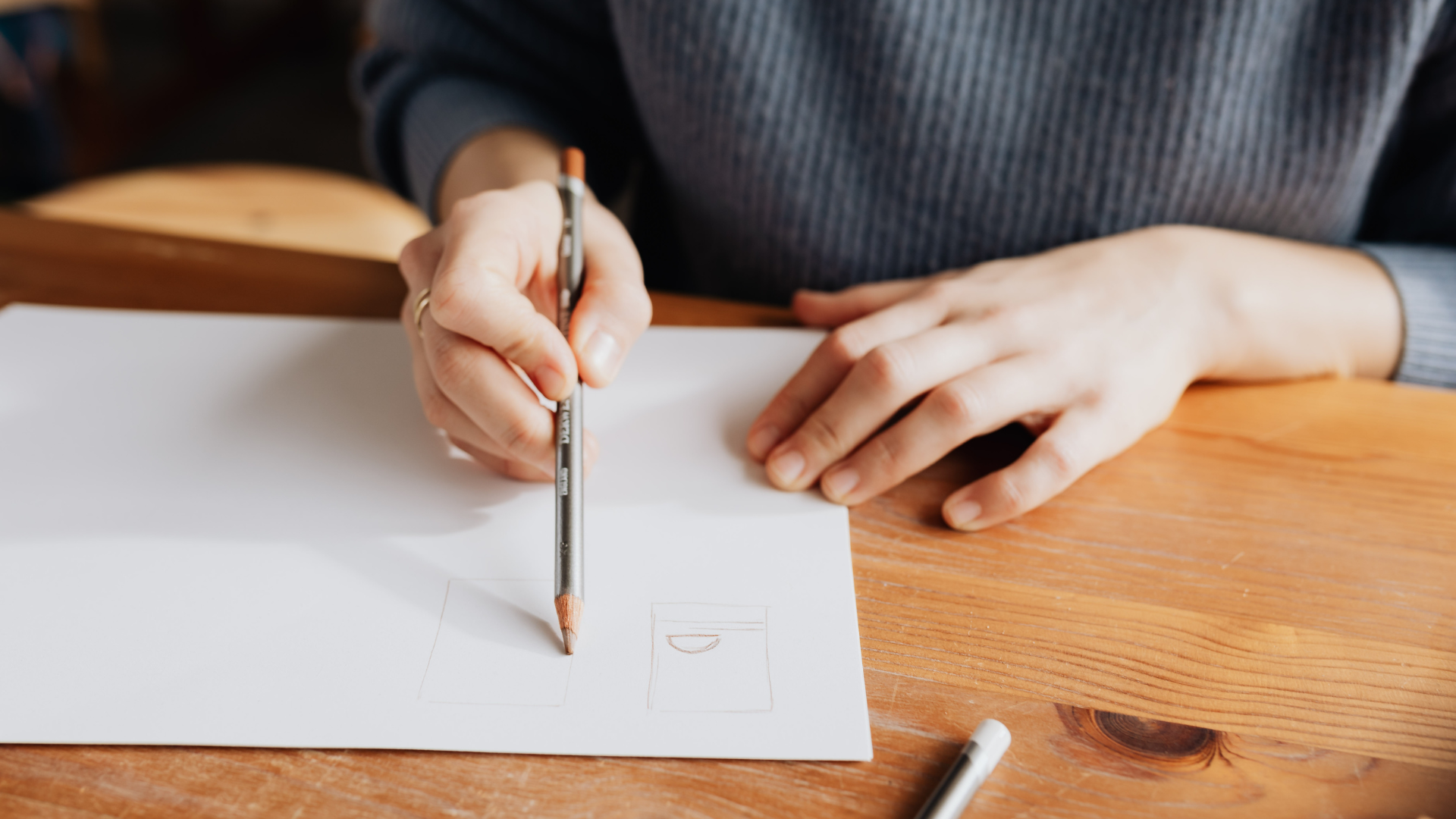 Une personne dessine au crayon de papier sur une feuille