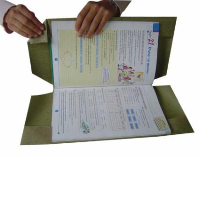 Mains qui mettent une couverture autour d'un livre scolaire