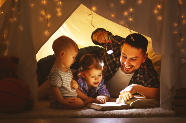 parents et enfants dans une tente en train de lire un livre