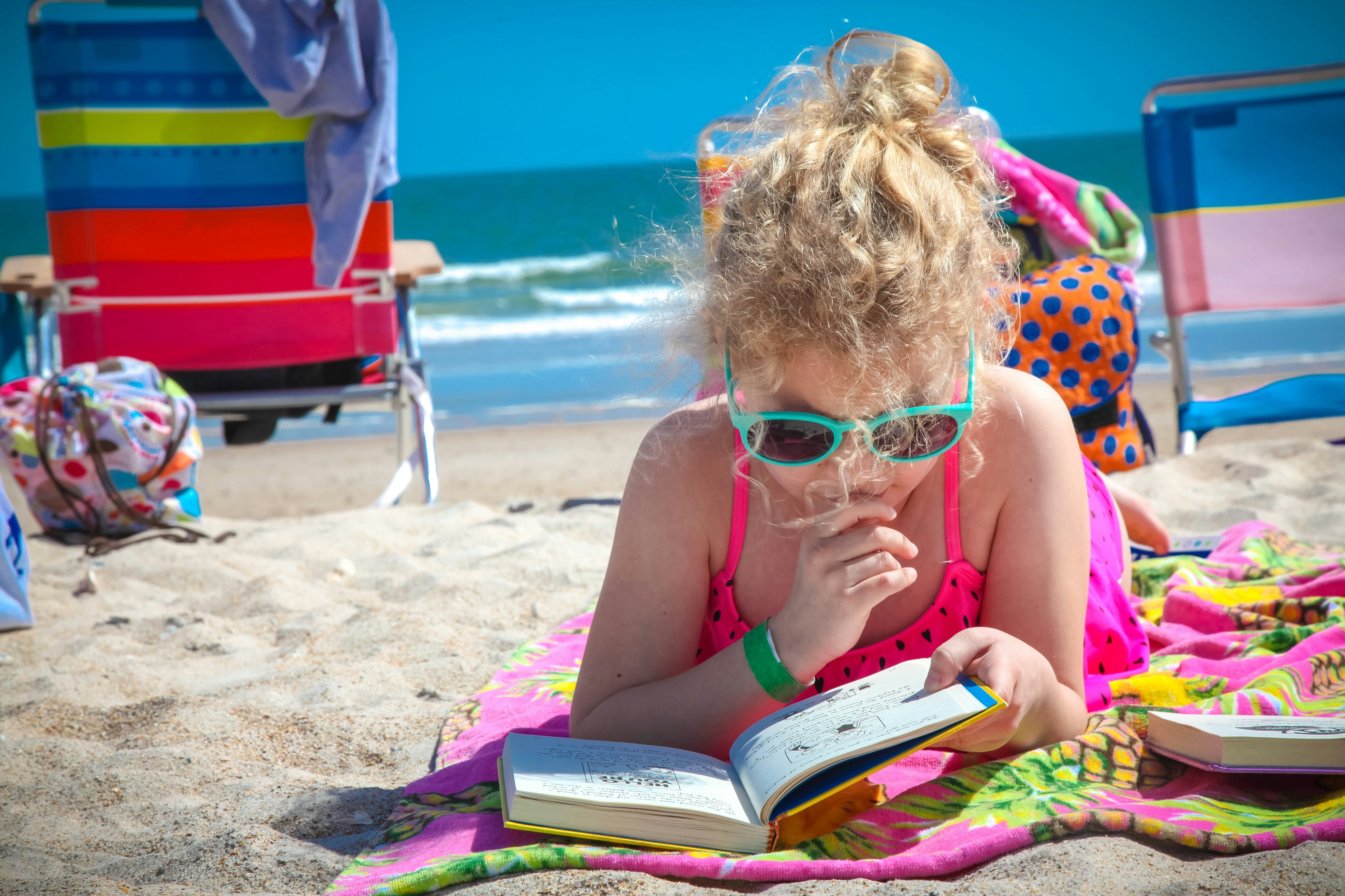 une petite fille sur la plage qui lit